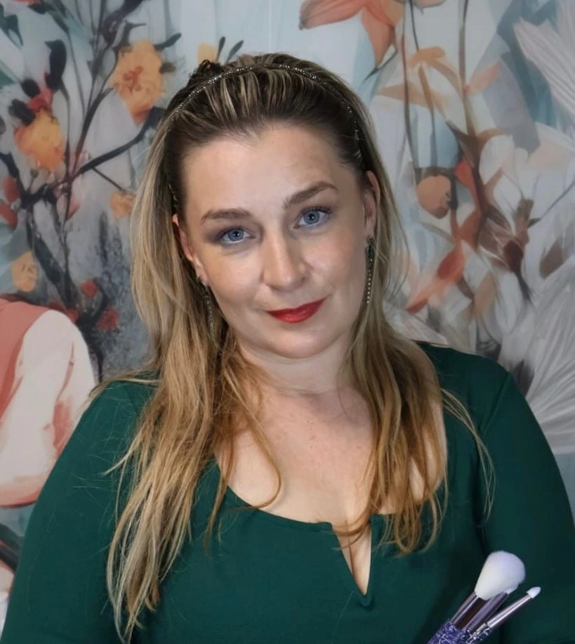 Ema Kotkova mit Make-up-Pinseln vor einer floralen Wand
